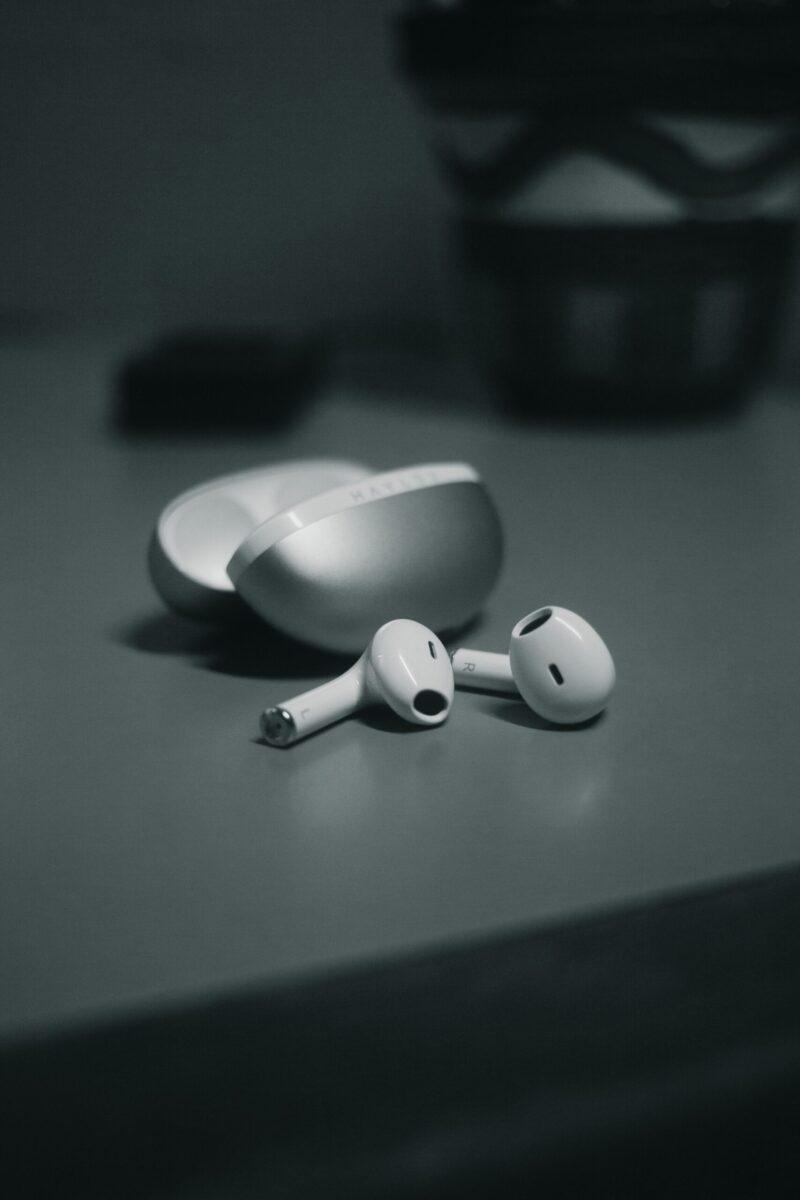 Minimalistic close-up of wireless earbuds with sleek design on a table in monochrome.