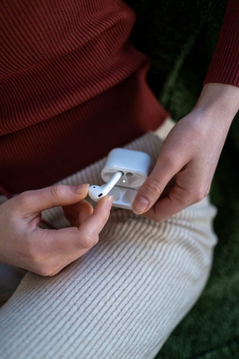 Close-up of a woman holding wireless earbuds in a case, emphasizing technology and lifestyle.